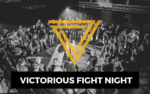 Eine Menschenmenge bildet einen Kreis um einen Kampfring mit "Victorious Fight Night" und STRONGER - die Männerarbeit der Liebenzeller Mission.