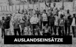 Eine bunt gemischte Gruppe lächelt im Freien; AUSLANDSEINSÄTZE und STRONGER - die Männerarbeit der Liebenzeller Mission sind fett gedruckt.