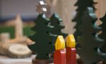 Hölzerne Weihnachtsbäume und rote Kerzen leuchten auf einem Tisch auf dem Missionsberger Adventsbasar.