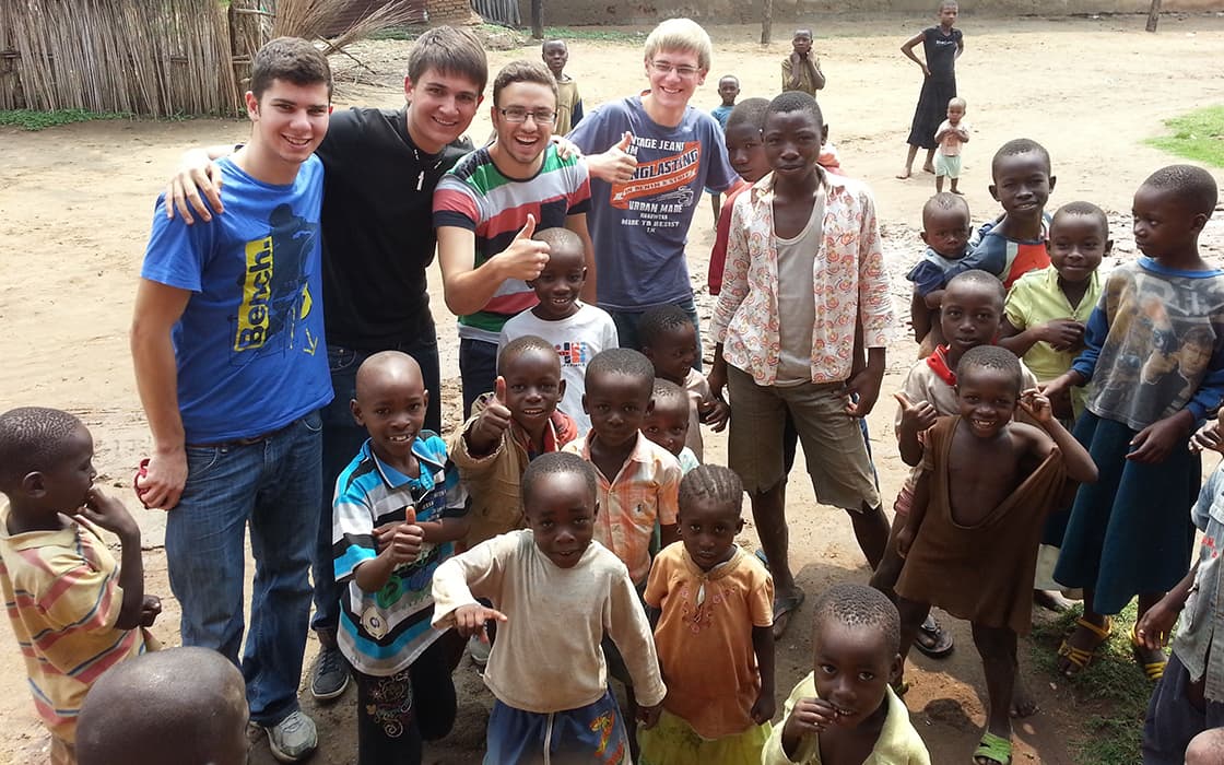 Eine Gruppe lächelnder junger Erwachsener und Kinder posiert mit Projekt Leben und BAHO im ländlichen Burundi im Freien.