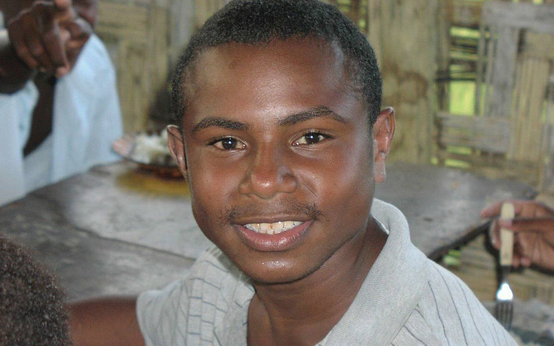 Maria Molnar lächelt in die Kamera, während sie in einem Innenraum des Bibelschulungszentrums mit anderen im Hintergrund sitzt.