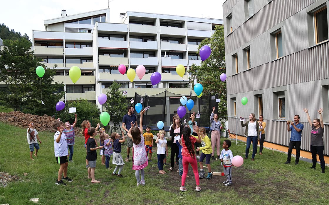 Kinder und Erwachsene spielen mit bunten Luftballons vor dem Hoffnungshaus in Bad Liebenzell, Deutschland.
