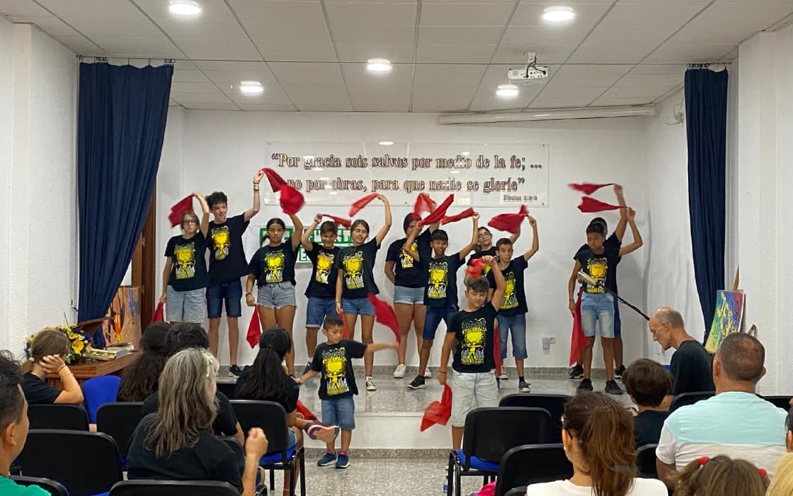 Kinder auf der Bühne, die in einem kleinen Auditorium an der Costa del Sol einen Tanz mit roten Tüchern aufführen.