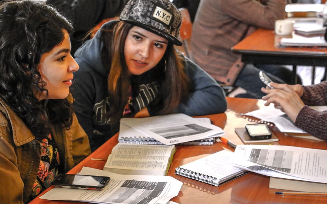 Zwei junge Frauen in Chile sitzen an einem Tisch und studieren, während sie sich über Mission Mobilizing unterhalten.