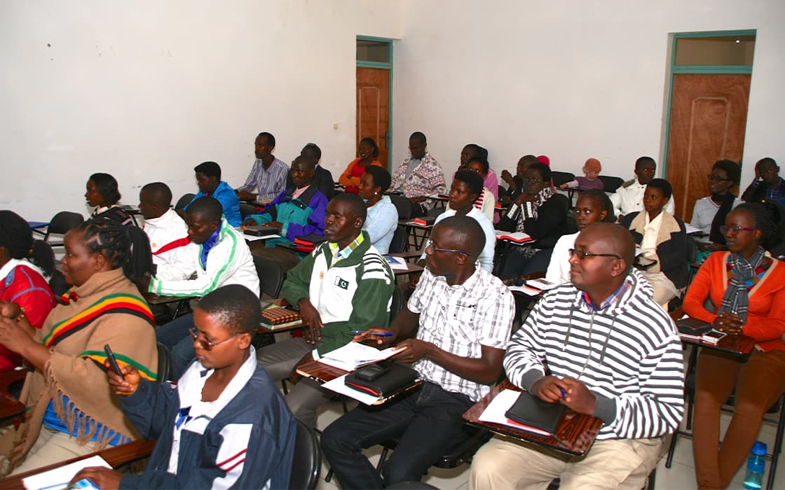 Ein Klassenzimmer voller Schüler, die an der theologischen Ausbildung teilnehmen, schreiben oder aufmerksam einer Lektion zuhören.