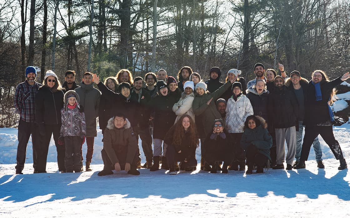 Eine große Gruppe der Reach Community Church posiert auf dem verschneiten Gelände in Kanada, dick eingepackt, lächelnd und winkend.
