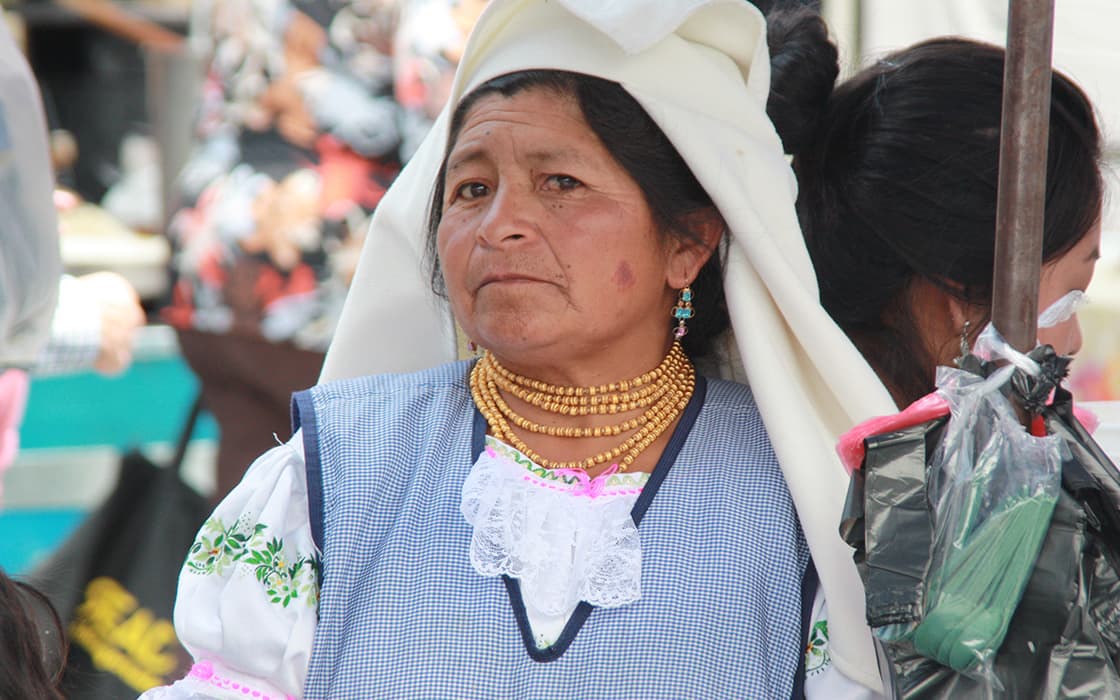 Eine ältere Frau in traditioneller Kleidung steht im Freien und repräsentiert die Initiativen Casa Ágape Ecuador und Hilfe für Frauen.