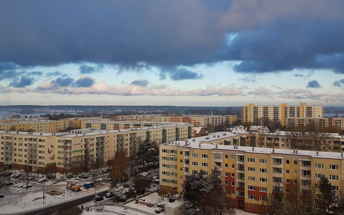 Schneebedeckte Wohnhäuser in Rostock, Deutschland, unter einem bewölkten Himmel in einer winterlichen Stadtlandschaft.