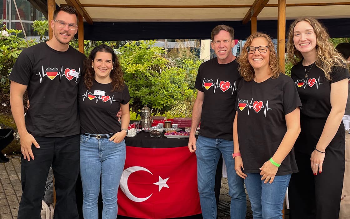 Fünf Personen lächeln vor einer türkischen Flagge, die Shirts der Lifepoint Church mit Herz- und Flaggenmotiven in Stuttgart tragen.