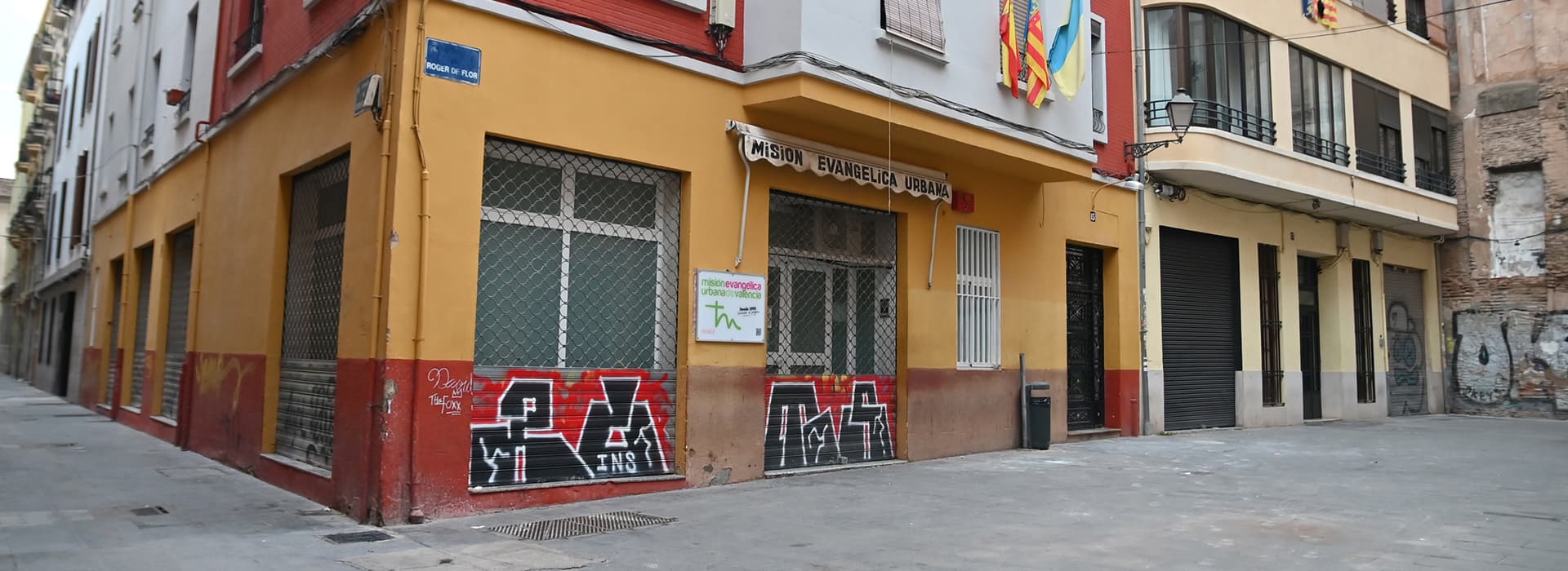 Eckgebäude mit roten und gelben Wänden in Valencia, Spanien; Graffiti markiert seinen Sockel in der ruhigen Misión Urbana.