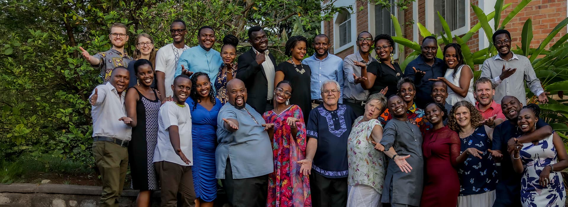 Eine große, bunt gemischte Gruppe in Burundi steht im Freien, lächelt und posiert im Grünen, um Gemeindegründungen zu feiern.