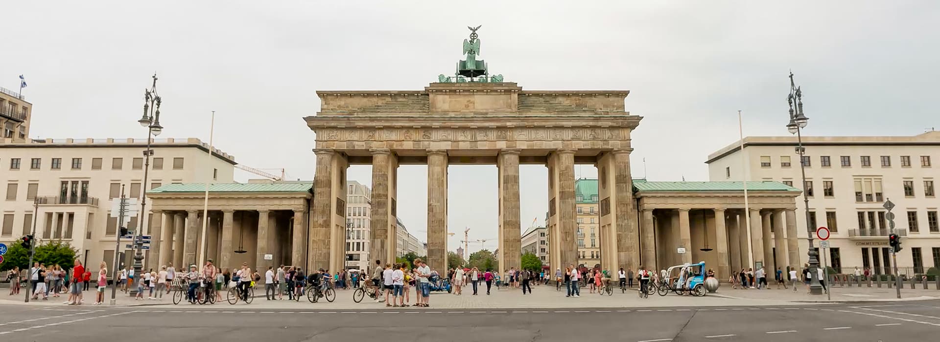 Das Brandenburger Tor in Berlin mit vielen versammelten Menschen, die Gemeindegründungen Berlin an einem bewölkten Tag widerspiegeln.