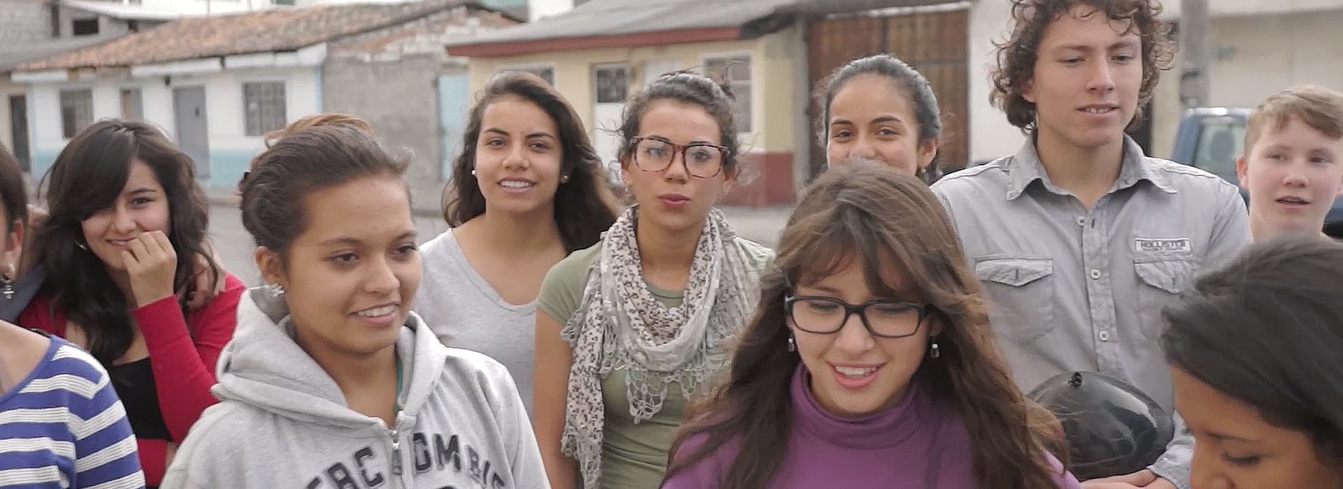 Eine Gruppe lächelnder Jugendlicher, die sich an der Jugendarbeit Ecuador beteiligen, steht draußen in einer Wohnstraße zusammen.