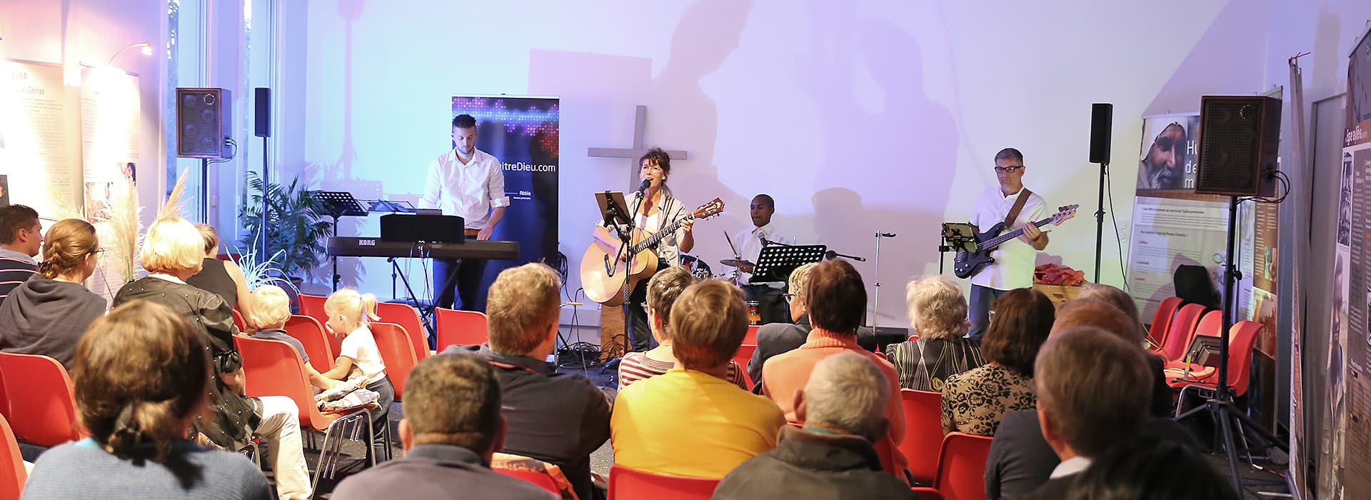 Auftritt einer Band auf der Bühne in der Normandie, Frankreich, während das Publikum von roten Stühlen aus zusieht - Teil der lokalen Gemeindegründungen.