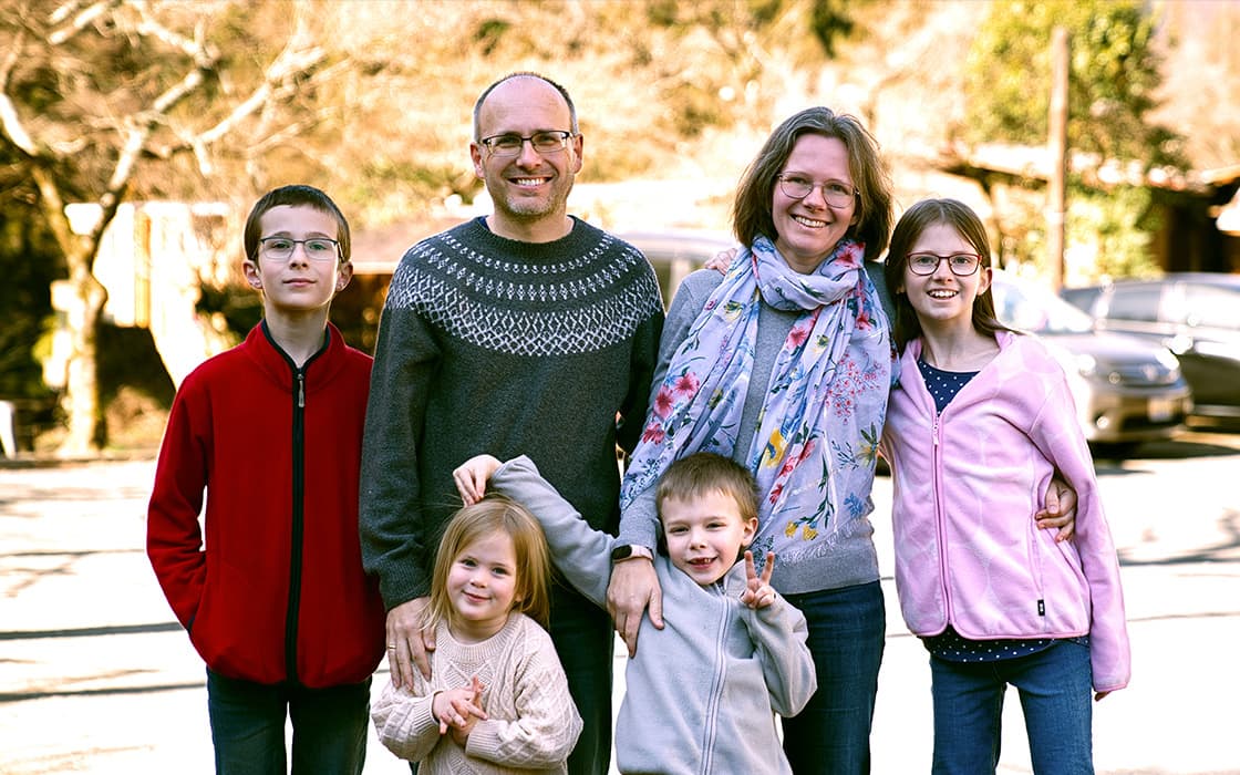 Eine lächelnde fünfköpfige Familie, darunter Andreas Gross und Rahel Gross, posiert im Freien mit den um sie versammelten Kindern.