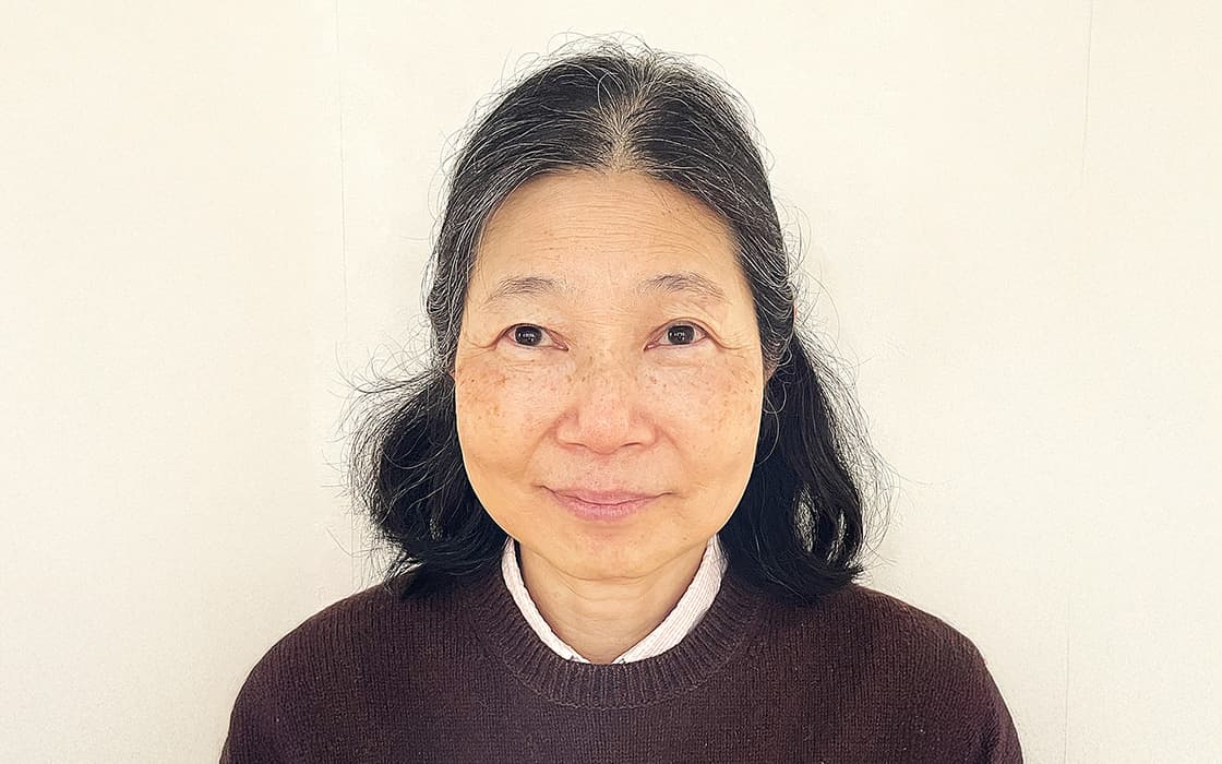 Porträt von Dr. Megumi Kondo, einer älteren Frau mit schulterlangem schwarzem Haar, lächelnd in einem dunklen Pullover vor einem schlichten Hintergrund.