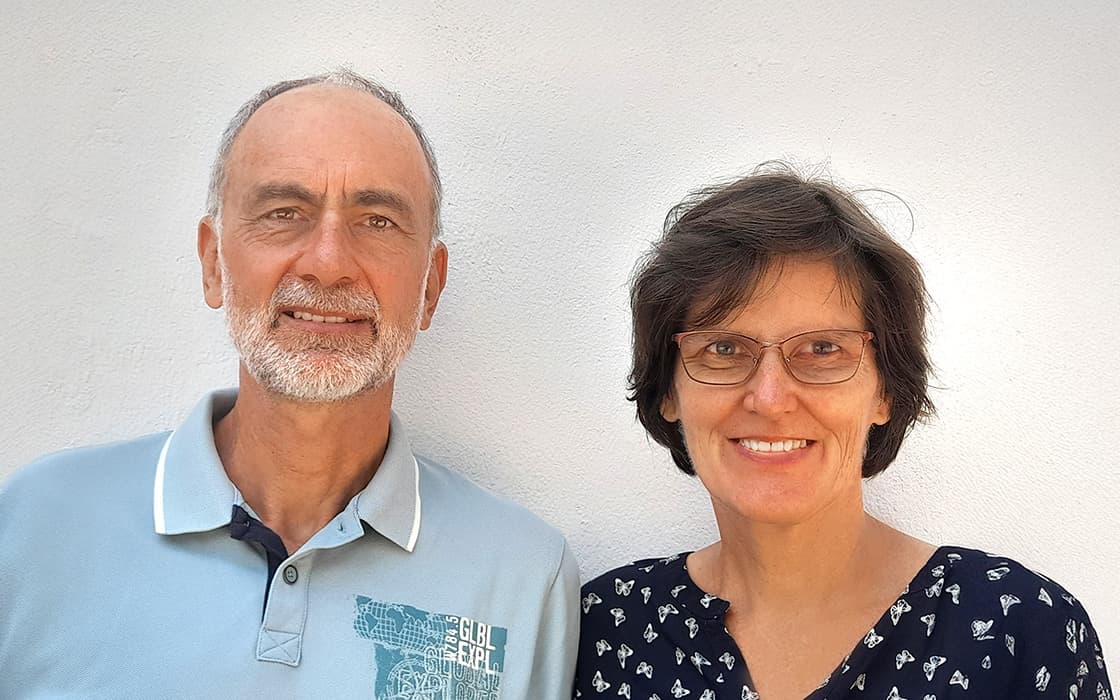 Zwei lächelnde ältere Menschen, Dorothe Kränzler und Paul Kränzler, stehen gemeinsam vor einer schlichten weißen Wand.