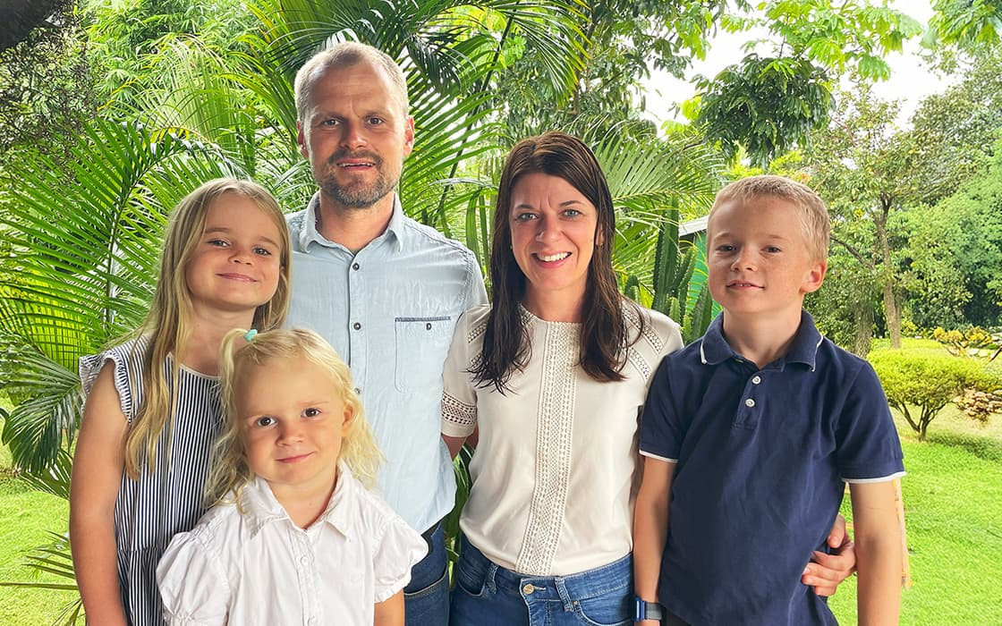 Eine fünfköpfige Familie, darunter Benjamin Wagner, posiert und lächelt mit Debora Wagner in einem üppigen grünen Garten.