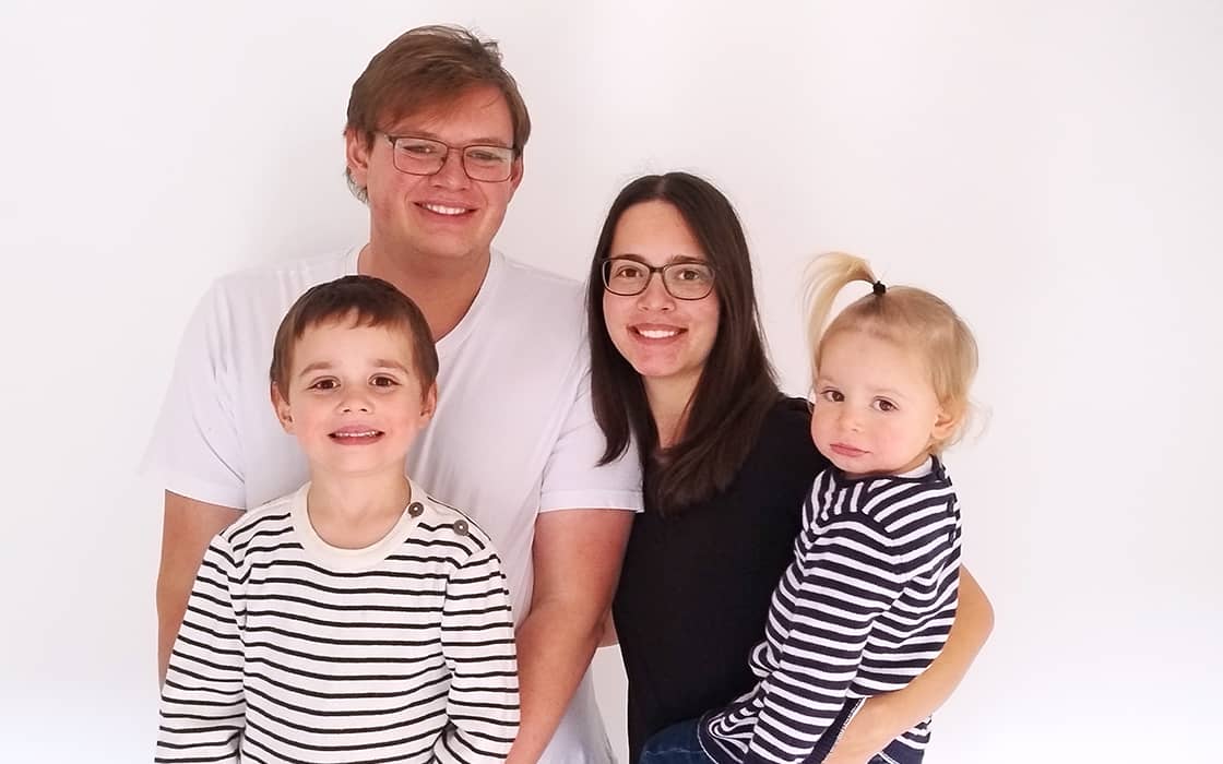 Eine lächelnde vierköpfige Familie, darunter Soraya Franz und Julian Franz, posiert in gestreiften Hemden vor einem weißen Hintergrund.