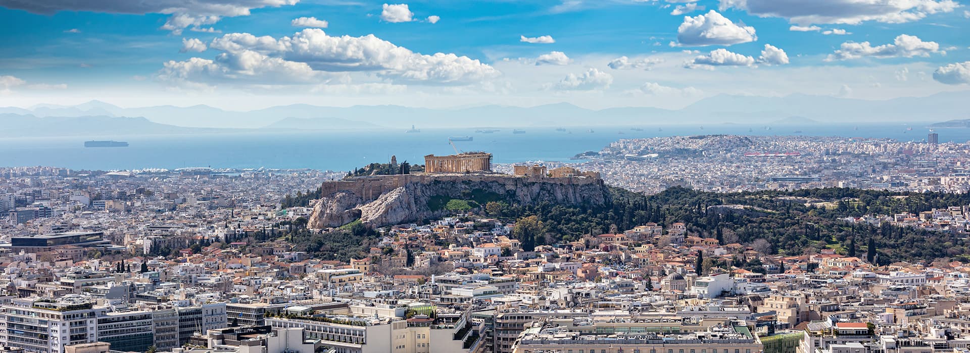 Luftaufnahme von Athen mit dem Akropolis-Hügel, aufgenommen von Elias Boucherit, bei klarem blauem Himmel.