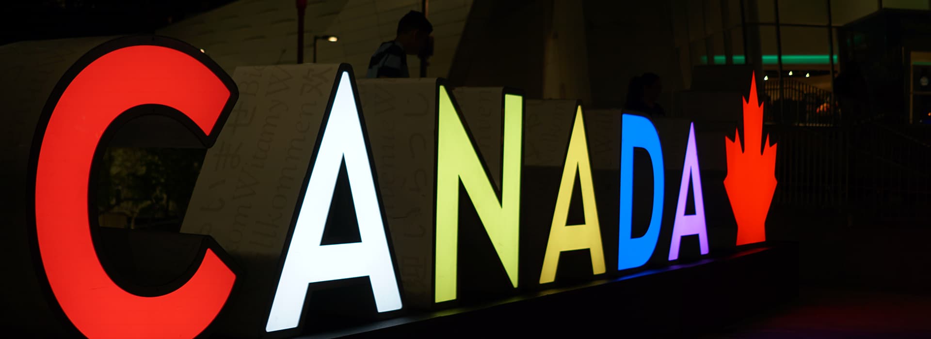 Beleuchtetes CANADA-Zeichen bei Nacht mit einem roten Ahornblatt-Symbol, fotografiert in einer dunklen Außenumgebung.
