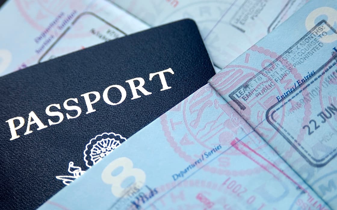 Nahaufnahme eines Reisepasses, der teilweise in die Seiten eingeklappt ist und verschiedene Ein- und Ausreisestempel aus Griechenland zeigt.