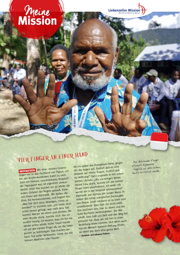 Ein älterer Mann lächelt und hält vier Finger hoch, um seine Meine Mission im April 2019 mitzuteilen; im Hintergrund sind Menschen und Bäume zu sehen.