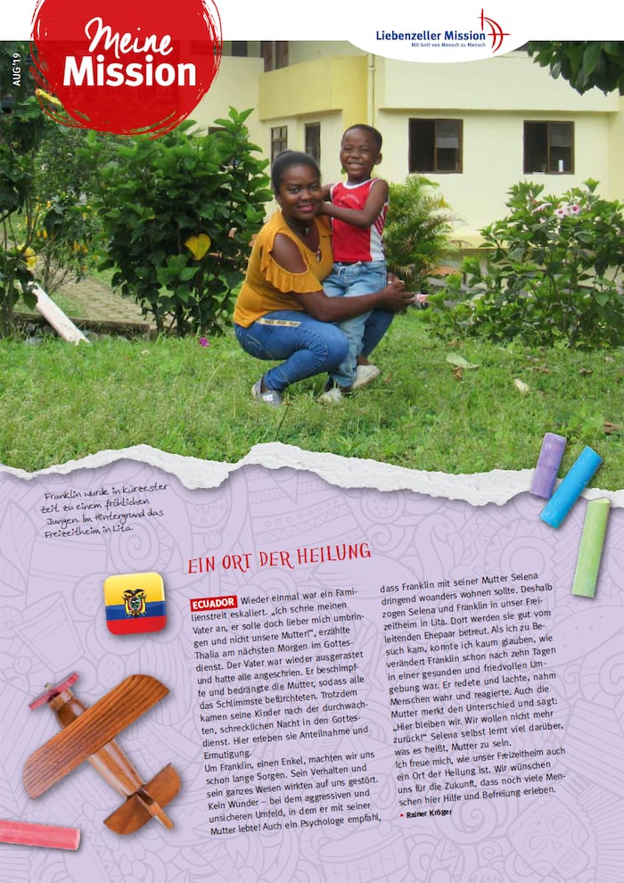 Eine lächelnde Frau kniet im Gras und umarmt ein fröhliches Kind während einer Mission im August 2019, dahinter ein gelbes Gebäude.