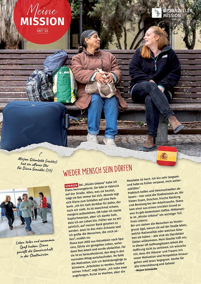 Zwei Frauen sitzen auf einer Bank mit Gepäck, unterhalten sich und lächeln; unter ihnen erscheinen "Mission Oktober 2025" und eine spanische Flagge.