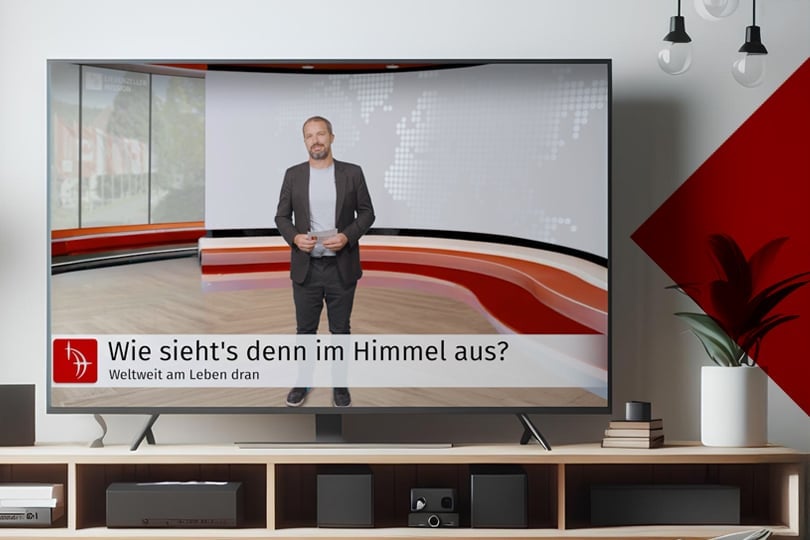 Ein Fernseher zeigt einen Sprecher in einem modernen Studio mit der Schlagzeile "Wie sieht's denn im Himmel aus?" Eine TV-Sendung der Liebenzeller Mission.