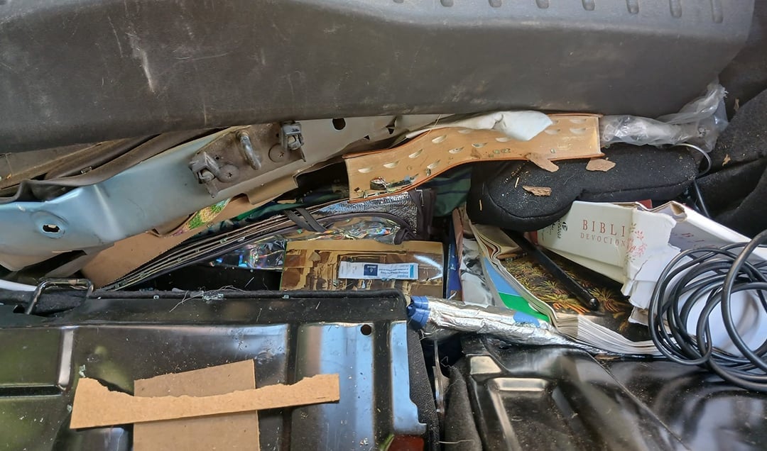 Ein Kofferraum, gefüllt mit verstreuten Gegenständen, darunter Bücher, Kabel und Materialien.