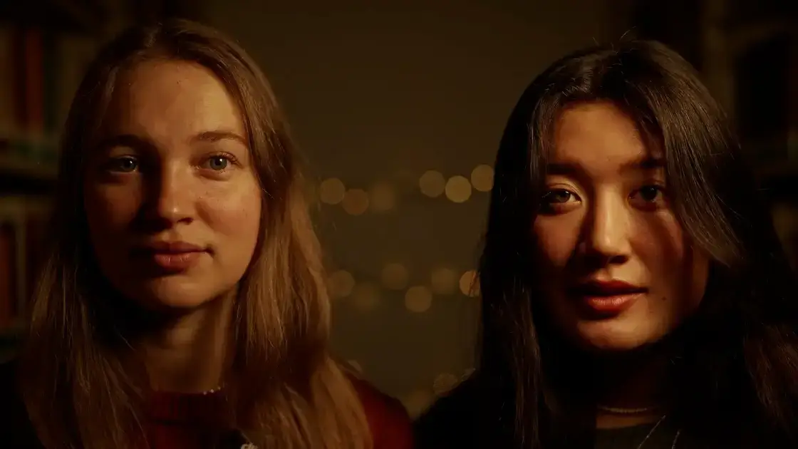 Zwei Frauen stehen als Lichtschenker nebeneinander, in weiches, warmes Licht getaucht, mit Regalen und glitzernden Lichtern im Hintergrund.