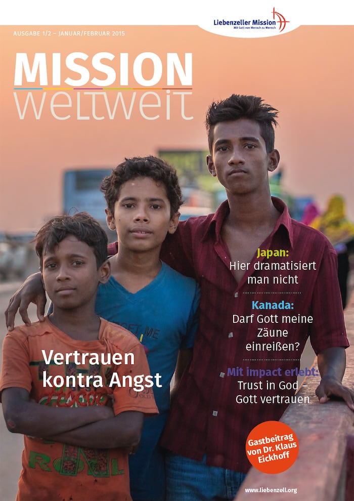 Drei Jungen stehen im Freien dicht beieinander und blicken in die Kamera. Der Text der Zeitschrift ist auf Deutsch und Englisch eingeblendet.