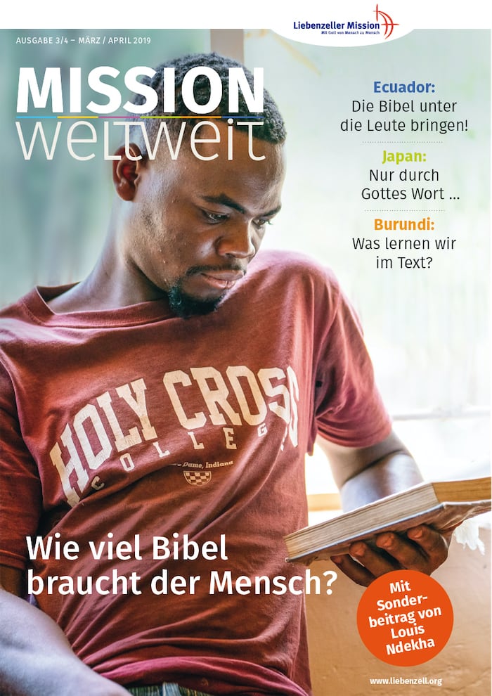 Ein Mann im Hemd des Holy Cross College liest ein Buch, während er am Fenster sitzt; ein deutscher religiöser Text überlagert das Bild.