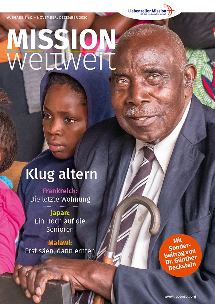 Ein älterer Mann mit einem Stock sitzt neben einem jungen Mädchen, beide blicken nach vorne, und der Text der Zeitschrift ist auf Deutsch.