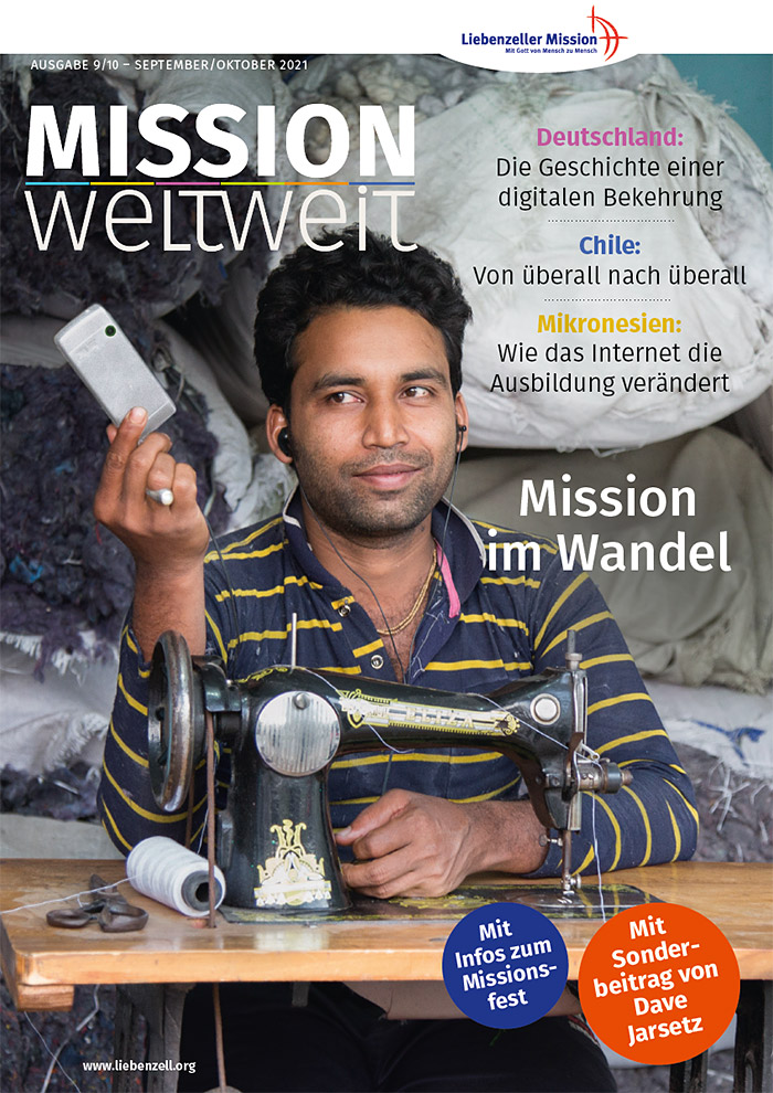 Ein Mann sitzt an einer Nähmaschine, lächelnd, mit Stoff- und Garnspulen um ihn herum. Ein Text in deutscher Sprache überlagert das Bild.