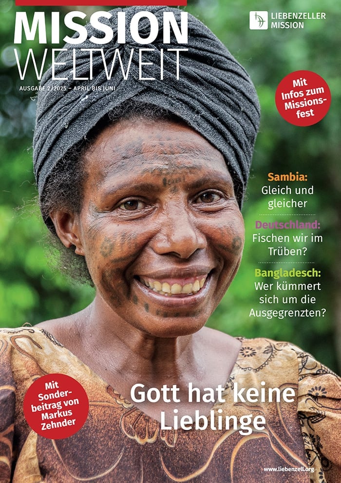 Lächelnde Frau mit Kopftuch und Gesichtstattoos steht im Freien vor grünem Laub, Titelbild einer deutschen Zeitschrift.