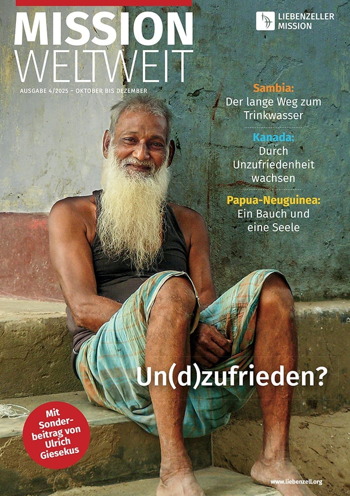 Ein älterer Mann mit langem weißen Bart sitzt barfuß auf einer Treppe und lächelt sanft; ein deutscher Text überlagert das Bild.