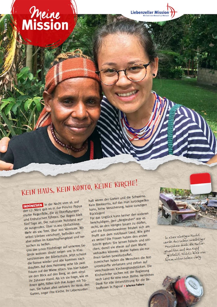 Zwei Frauen lächeln und umarmen sich im Freien, eine trägt eine Brille und Perlen, die andere ein gemustertes Kopftuch.