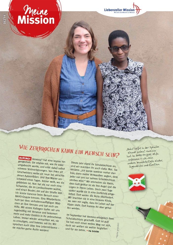 Zwei Frauen stehen lächelnd nebeneinander vor einer beigen Wand, unter der sich Texte und Grafiken über eine Mission in Burundi befinden.