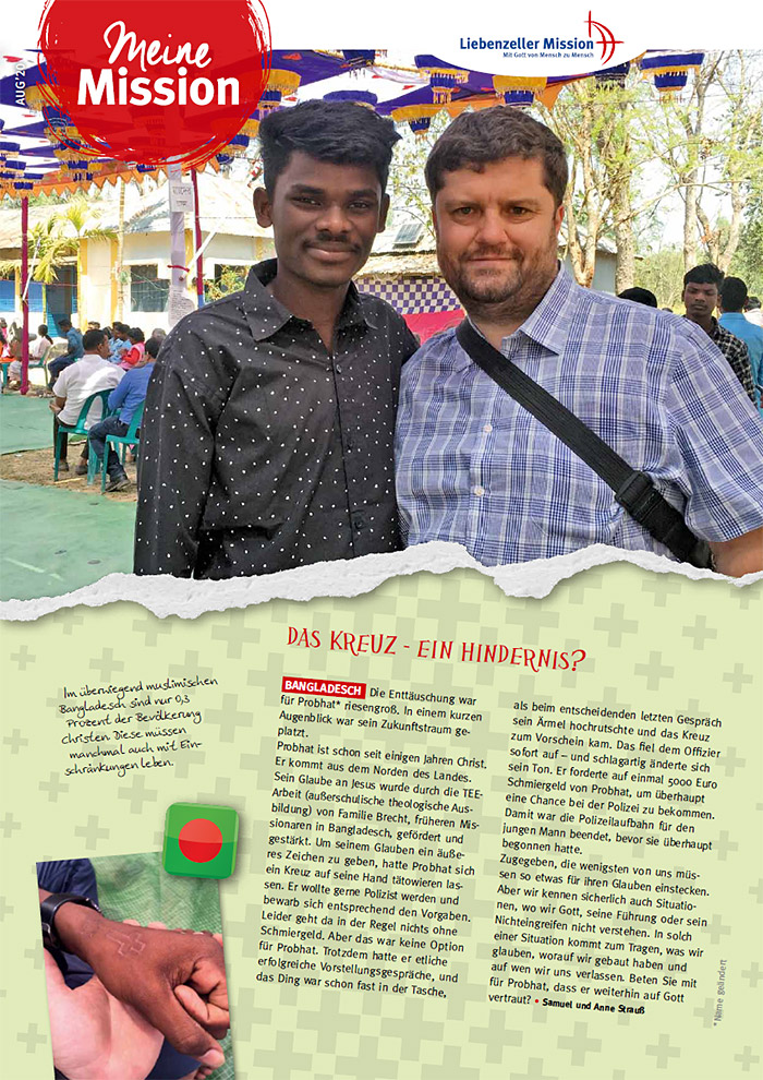 Zwei Männer stehen lächelnd mit den Armen umeinander bei einer Veranstaltung im Freien; im Hintergrund sind Dekorationen und Menschen zu sehen.