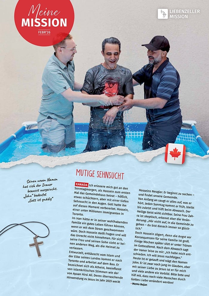 Drei lächelnde Männer stehen während einer Taufe in einem kleinen Becken, wobei ein Mann getauft wird und zwei ihn unterstützen.