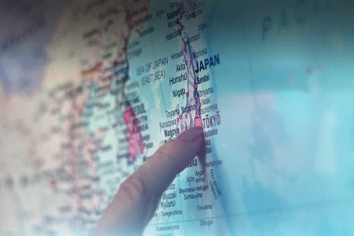 Eine Hand zeigt auf einer Karte auf Tokio, Japan, wobei auch die umliegenden Städte und Regionen sichtbar sind.