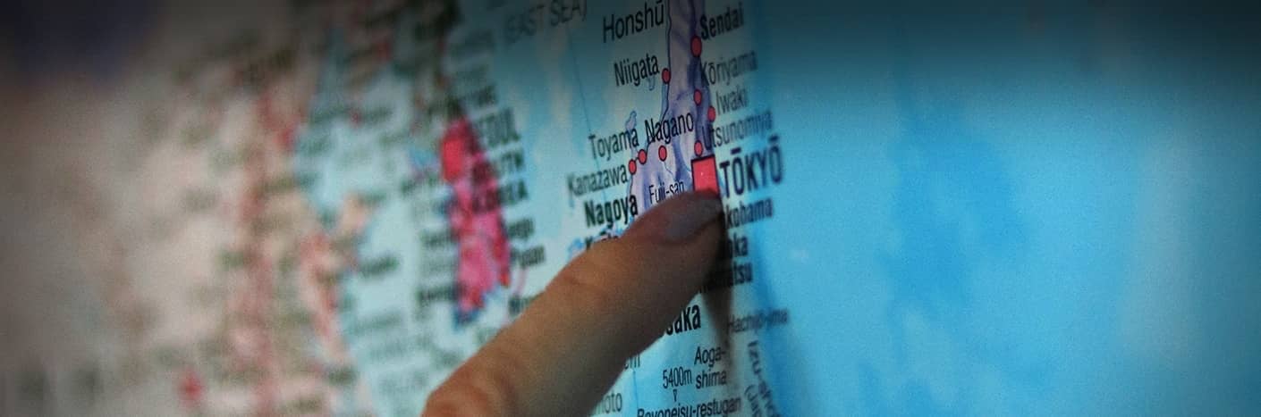 Ein Finger zeigt auf einer Karte Japans auf Tokio, wobei die umliegenden Städte und Regionen sichtbar sind.