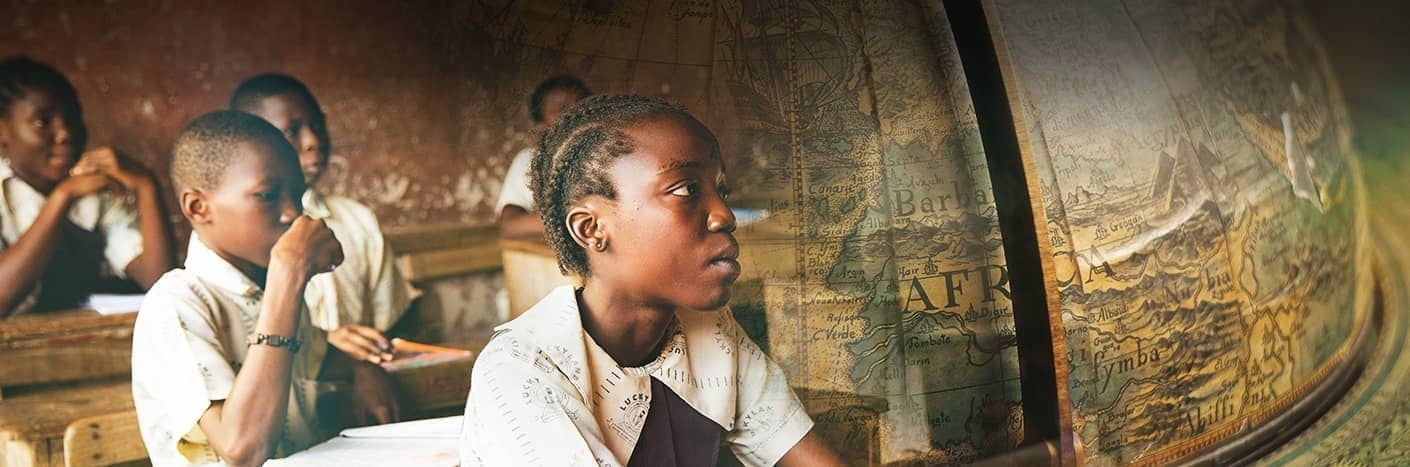 Schüler in Uniform sitzen aufmerksam in einem Klassenzimmer, im Hintergrund ist eine verblasste Karte von Afrika zu sehen.