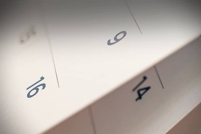 Nahaufnahme eines Papierkalenders mit den Zahlen 9, 14 und 16 auf separaten Seiten.