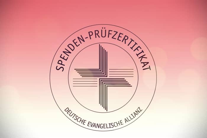 Kreisförmiges Spenden-Prüfzertifikat-Siegel mit Kreuzlogo der Deutschen Evangelischen Allianz auf rosafarbenem Farbverlaufs-Hintergrund.