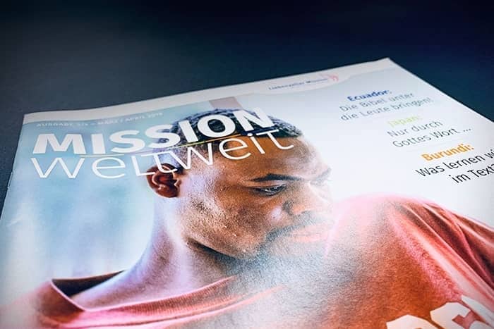 Nahaufnahme des Titelblatts einer Zeitschrift mit dem Titel MISSION weltweit, auf dem ein Mann nach unten schaut.