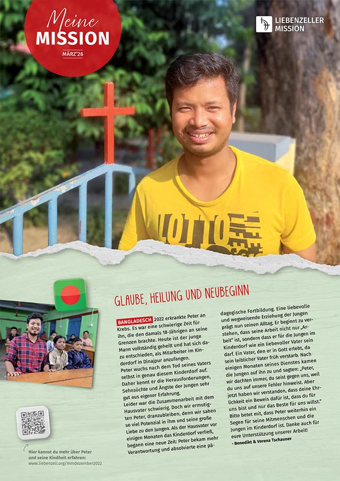 Ein lächelnder Mann steht draußen neben einem blauen Kreuz und einem Baum, mit deutschen Texten und Fotos über seine Missionsarbeit in Bangladesch.