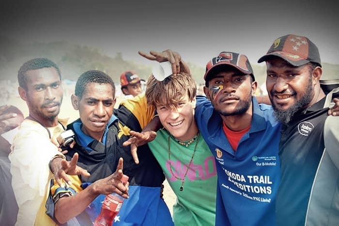 Eine Gruppe von fünf lächelnden Männern steht im Freien dicht beieinander und legt die Arme umeinander.